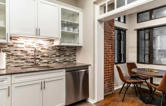 a kitchen with white cabinets and a sink and a table with chairs