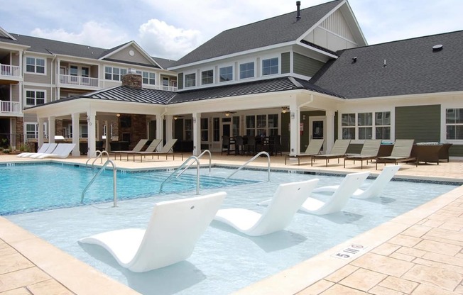 a large swimming pool with white chairs in front of a building