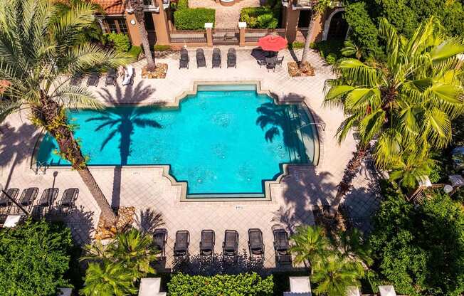 Overhead view of Mediterranean-style clubhouse and pool with palm trees