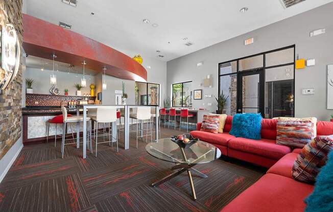 A living room with a red couch and a glass coffee table.