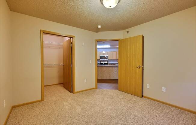 a bedroom with a door open to a closet. Fargo, ND East Bridge Apartments