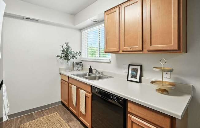 A kitchen with wooden cabinets and a black dishwasher.