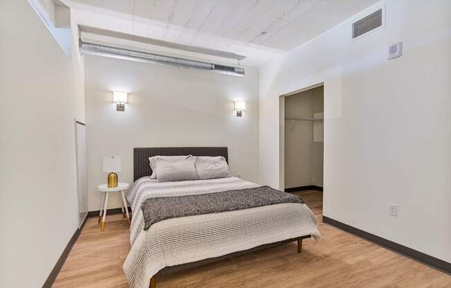 A bedroom with a bed, nightstand, and a lamp.