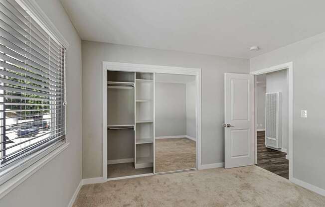 A room with a carpeted floor and a window with blinds.