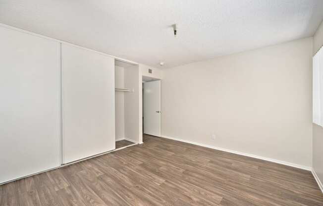 a bedroom with wood floors and a closet