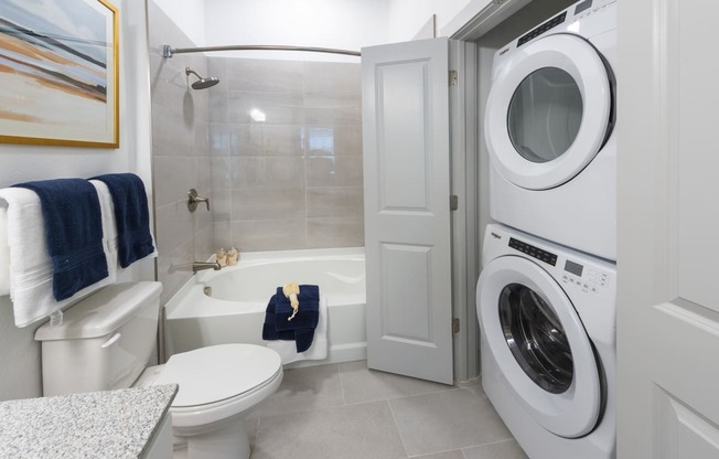 a bathroom with a washer and dryer in it and a toilet and tub