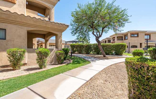 A beige house with a tree in front of it.