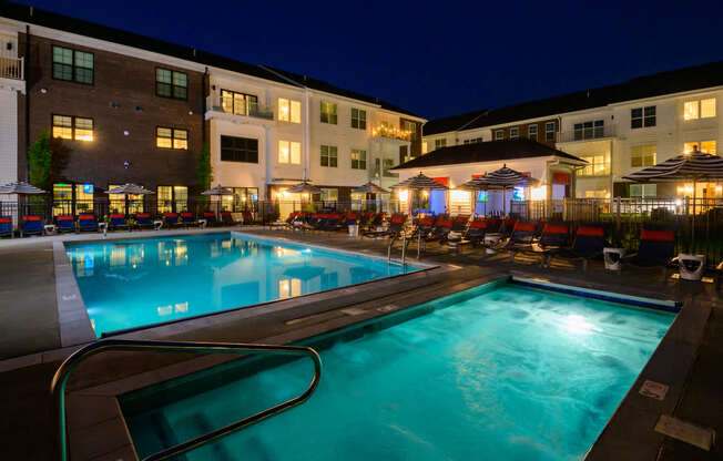 A swimming pool at a resort with a lit patio area.