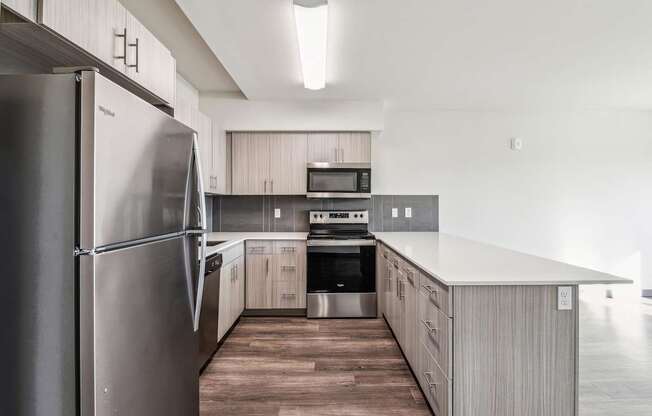 A modern kitchen with a stainless steel refrigerator and wooden flooring.