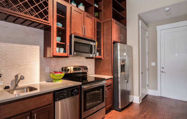 View of Kitchen, Showing Plank-Wood Flooring, Stainless Steel Appliances, and Custom Cabinetry at Alpha Mill Apartments