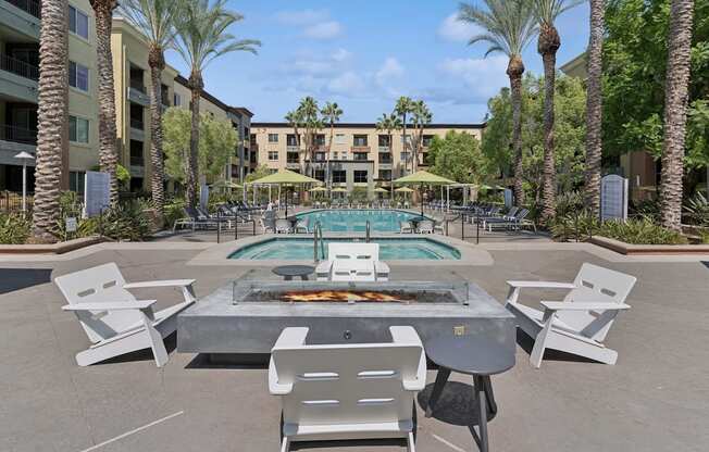 A pool surrounded by palm trees and chairs at The Kitt at Warner Center Apartments, California, 91303