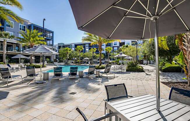 a patio with tables chairs and umbrellas and a pool