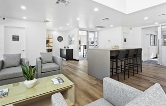 a living area with couches a coffee table and a kitchen in the background