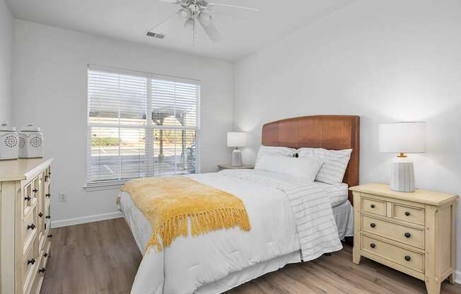 A bedroom with a large bed, a dresser, and a ceiling fan.