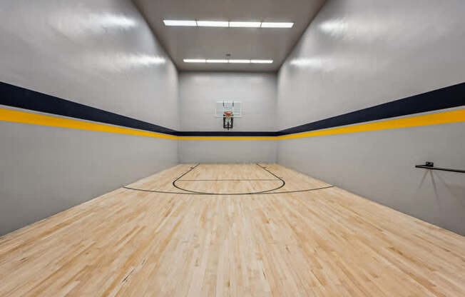 A basketball court with a wooden floor and a basketball hoop.