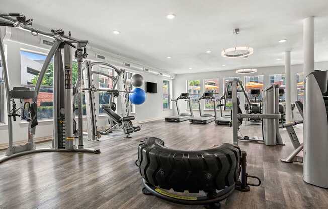 A gym with a variety of equipment including treadmills, weights, and exercise machines.