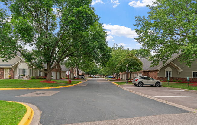 A residential street with houses on both sides and a car parked on the right side.