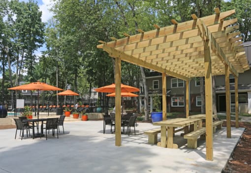 a patio with a pergola and tables with umbrellas