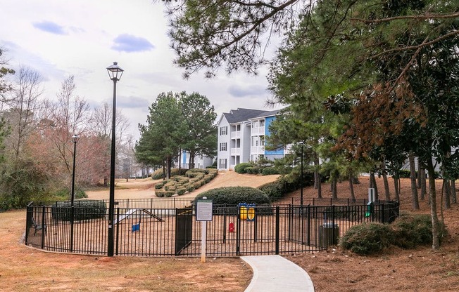 a park with a fence and a building in the background