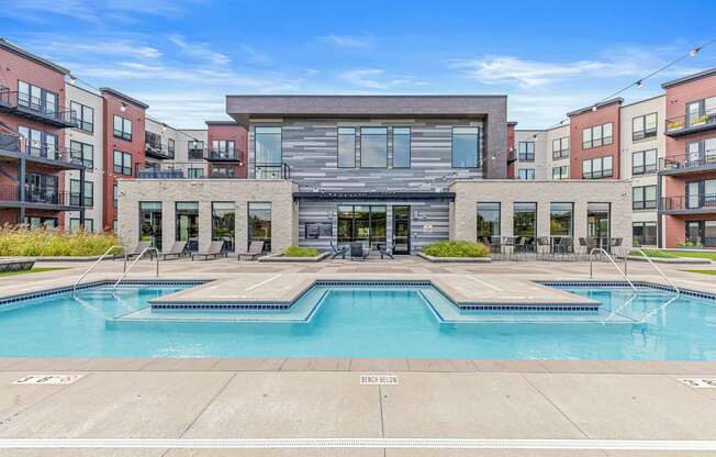 A large swimming pool in front of a building with a glass facade.