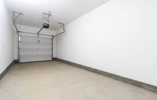 A garage with a white wall and a grey floor.