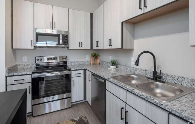 A modern kitchen with granite countertops and stainless steel appliances.