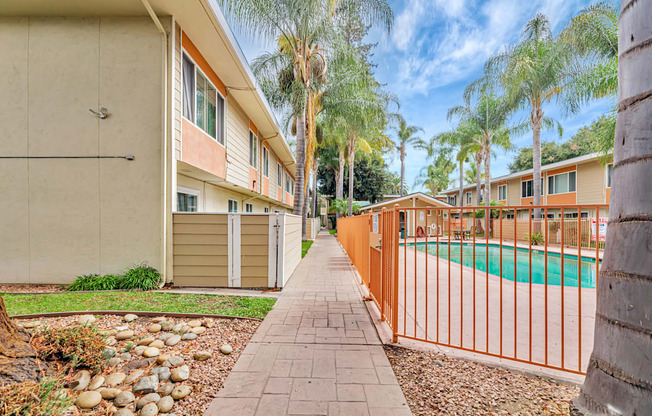 A row of houses with a pool and palm trees.