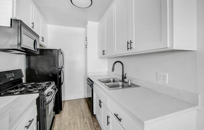 a kitchen with white cabinets and black appliances and a sink