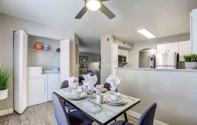 a dining room table and a kitchen with a ceiling fan