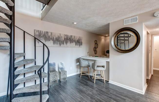 a living room with a spiral staircase and a bar with chairs