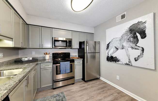 a kitchen with stainless steel appliances and a painting of a horse on the wall