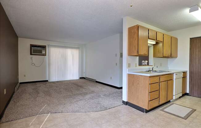 A living room with a glass sliding door with a kitchen. Fargo, ND Prairiewood Meadows