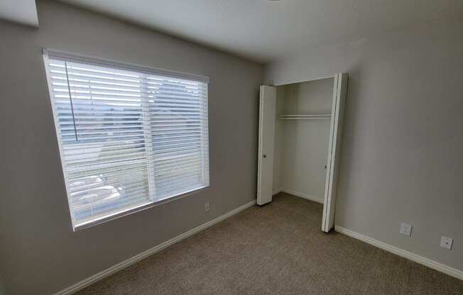 a bedroom with a large window and a closet