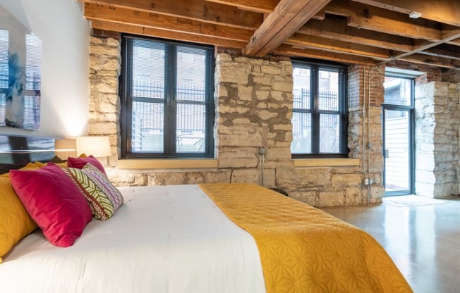 a bedroom with a bed and a stone wall