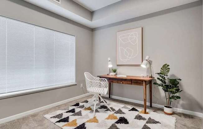 a home office with a large window and a desk with a chair. Circle Pines, MN Lexington Lofts