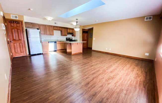 an empty living room and kitchen with wood flooring