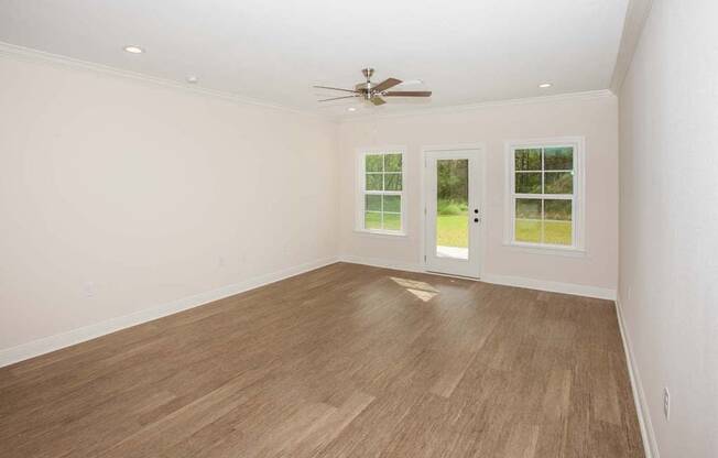 an empty living room with a ceiling fan and a window