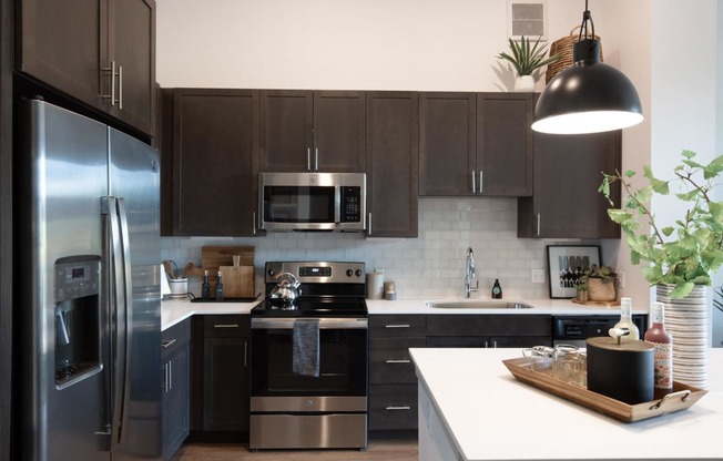 a modern kitchen with stainless steel appliances and dark cabinets