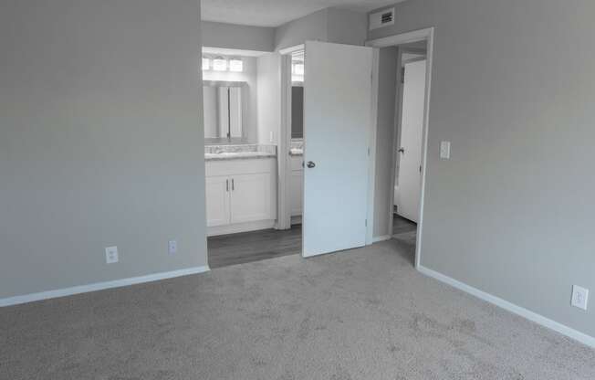 an empty living room with a white carpet and a bathroom