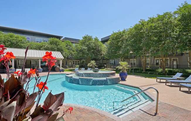 A pool surrounded by trees and a building in the background.
