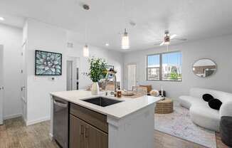 A modern kitchen with a large island and a living area with a sofa.