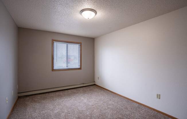 a bedroom with carpet and a window. Fargo, ND  Prairie Park Apartments