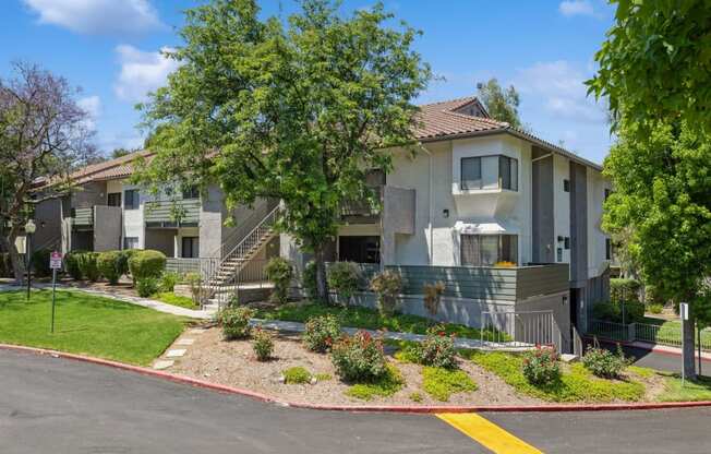 the outlook of an apartment building with a lawn and trees