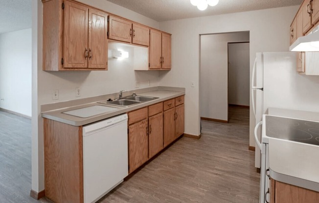 an empty kitchen with wooden cabinets and white appliances