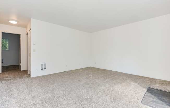 an empty living room with white walls and a carpeted floor