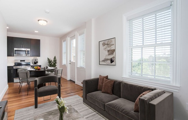 a living room with a couch and a chair and a kitchen with a dining room