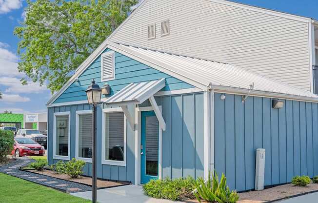 A blue house with a white roof and a red car parked in front.