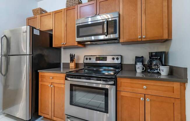 a kitchen with stainless steel appliances and wooden cabinets at Pier Village Apartments, New Jersey