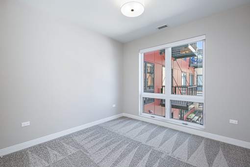 A room with a large window and a grey carpet.