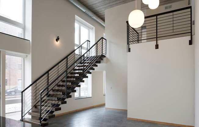 A staircase with a metal railing and a light hanging from the ceiling.